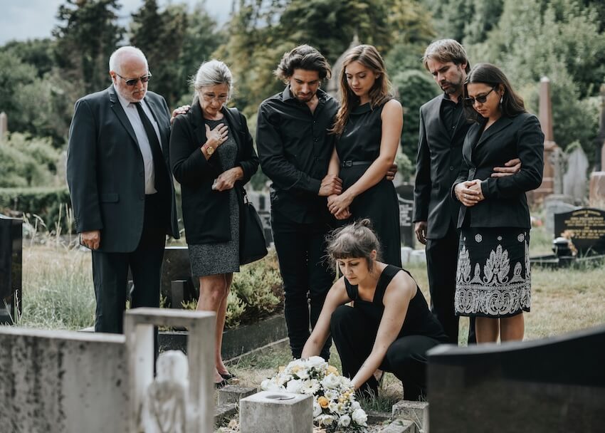 Funeral service announcement: family placing flowers on a grave